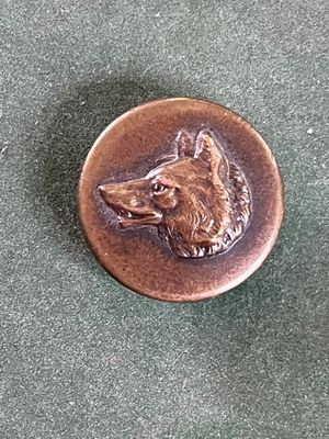un badge en métal sur lequel est représenté un chien