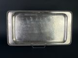 an antique silver tray with beaded edges on a black background
