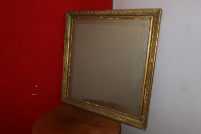 a mirror sitting on top of a stool next to a red wall