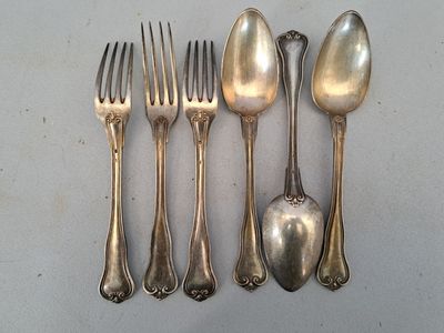 cinq cuillères en argent et une fourchette sur une table
