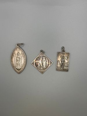 three silver pendants of the virgin mary and jesus