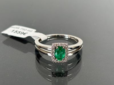 a close up of a diamond and emerald ring on a table