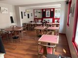 many tables and chairs in this restaurant with a red wall