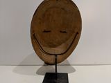 a wooden plate with a smiley face on it on a stand