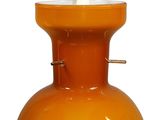 an orange vase with a white candle inside of it