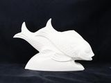 sculpture en céramique blanche représentant un poisson sur fond noir
