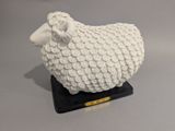 un mouton blanc posé sur un socle noir