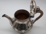 an antique silver tea pot with a lid on a white surface