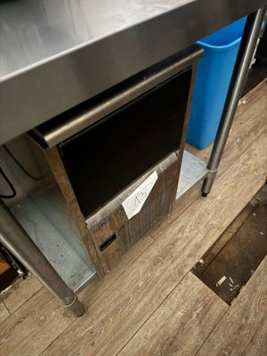 une table en acier inoxydable avec une poubelle bleue posée en dessous