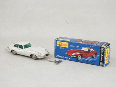 une petite voiture miniature posée à côté d'une boîte sur une surface blanche