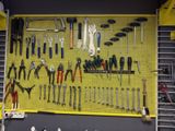 un panneau perforé jaune sur lequel sont accrochés de nombreux outils