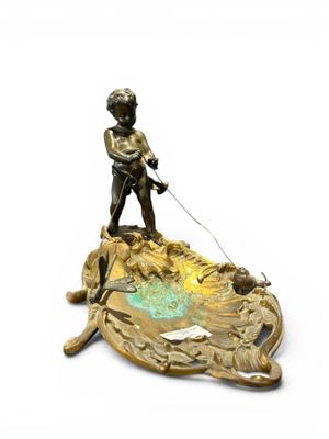 bronze figurine of a boy on a boat with a dog on a leash