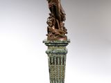 bronze statue of a woman holding a bird on a pedestal