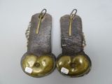 two pairs of shoes with gold buttons on them sitting on a white surface