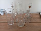 bottles and glasses on a wooden table with a cell phone in the background