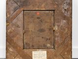 an old wooden frame with a plaque on it in front of a white wall