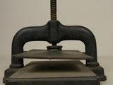 an old iron press is sitting on top of a white surface