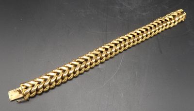 une image représentant un bracelet en or posé sur une surface noire