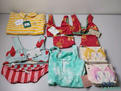beaucoup de vêtements de bébé et un sac à main posés sur une table