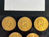 six gold coins in a plastic bag on a black surface