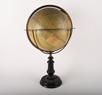 un vieux globe terrestre posé sur un socle noir, sur fond blanc