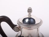 a silver tea pot with a wooden handle on a table