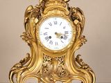 une horloge en or posée sur une table, surmontée d'une statue