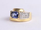 a close up of a gold ring with a blue sapphire and diamonds