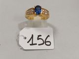 Gros plan sur une bague en or ornée d'une pierre bleue