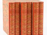 six livres rouges empilés les uns sur les autres sur une surface blanche