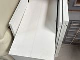 a white cabinet with a drawer in it next to a chair