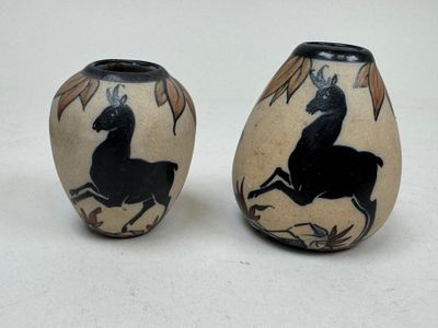 pair of black and white vases with horses on them on a white surface