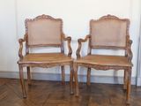 pair of wooden chairs with wicker seats on a parquet floor
