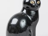 une figurine de chat noir posée sur une surface blanche
