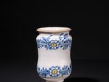 a white and blue vase sitting on top of a black table