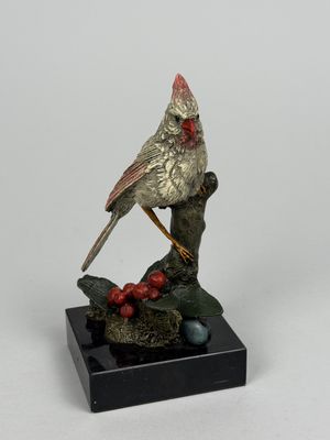 statue représentant un oiseau perché sur une branche ornée de baies