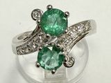 a close up of a ring with two emerald stones on it