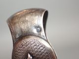 a close up of a silver vase with a bird on it