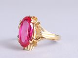 a close up of a pink stone ring on a white surface
