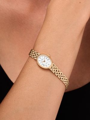 a woman wearing a gold bracelet with a white dial on her wrist