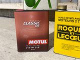 two cans of motor oil sitting next to each other on the ground