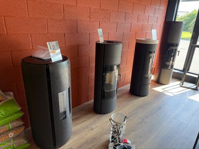 trois poubelles noires posées par terre à côté d'un mur de briques rouges