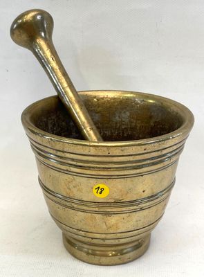 un mortier en laiton avec une cuillère en bois à l'intérieur