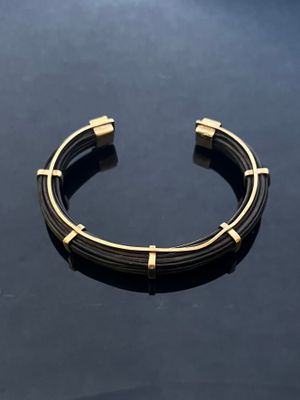a close up of a black and gold bracelet on a table
