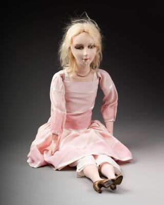 une image représentant une poupée assise par terre, vêtue d'une robe rose