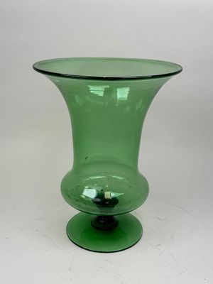 a green glass vase sitting on top of a white table