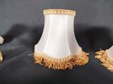 two white lamps with gold fringes on a black background