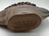a brown vase with writing on it sitting on a white surface