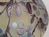 a close up of a glass vase with flowers and leaves on it