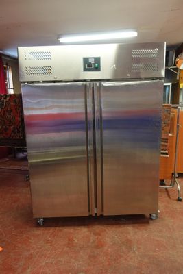 un grand réfrigérateur en acier inoxydable dans une cuisine équipée de placards orange